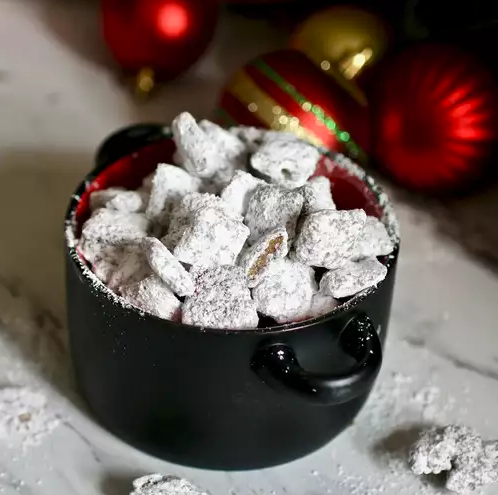 A bowl of homemade Muddy Buddies coated with powdered sugar, perfect for parties and snacks.