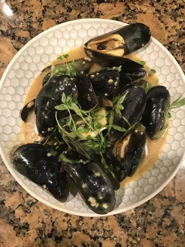 Close-up of Coconut Curry Mussels Omelette Roll with mussels cooked in a creamy coconut curry sauce, wrapped in a golden omelette and garnished with fresh cilantro and lime wedges.