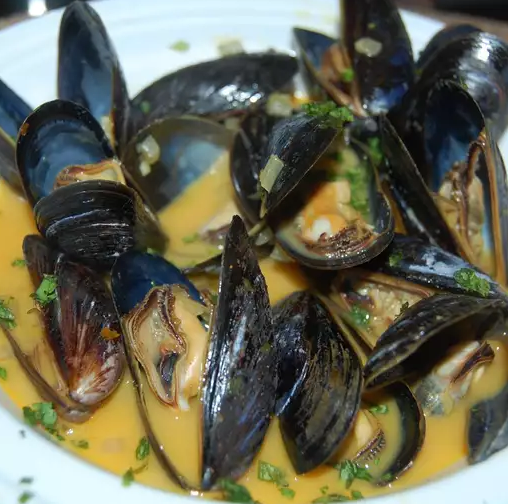 Close-up of Coconut Curry Mussels Omelette Roll with mussels cooked in a creamy coconut curry sauce, wrapped in a golden omelette and garnished with fresh cilantro and lime wedges.