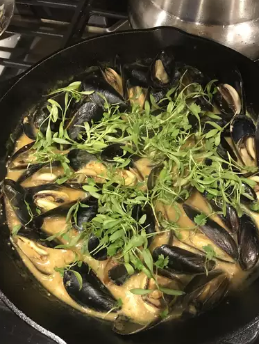 Close-up of Coconut Curry Mussels Omelette Roll with mussels cooked in a creamy coconut curry sauce, wrapped in a golden omelette and garnished with fresh cilantro and lime wedges.