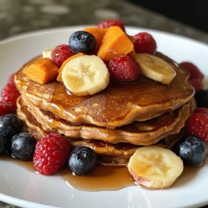 Stack of Protein-Packed Sweet Potato Pancakes with toppings like berries, yogurt, and syrup.